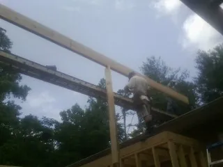 Carpenter setting a ridge beam over a new addition frame — Ice Dam Removal by Roofing Brothers in Woodlawn