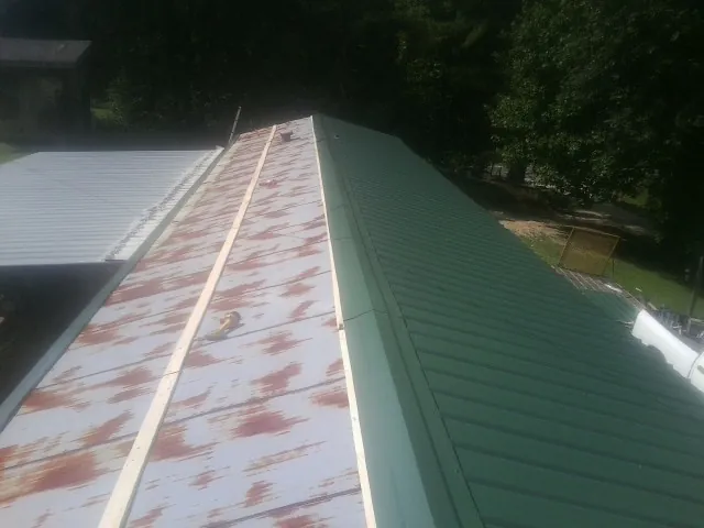 Old rusted panels beside newly installed green metal roofing — Wind Damage Roof Repair by Roofing Brothers in Woodlawn