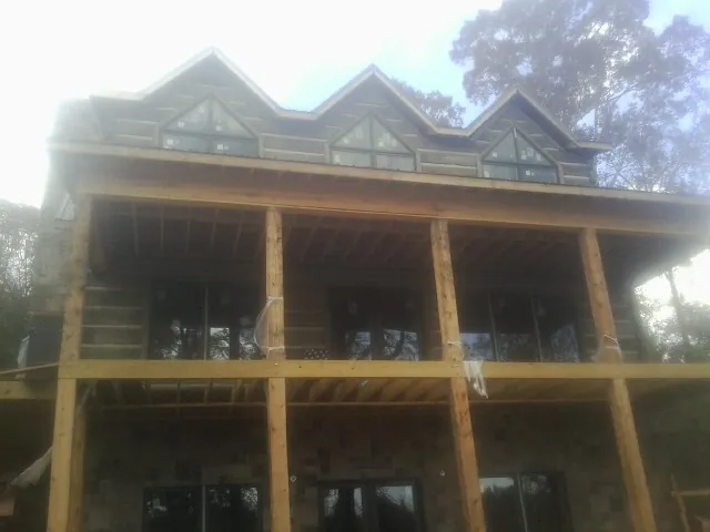 Dormers and porch framing on a large log home under construction — Roof Coating work by our crew in Woodlawn