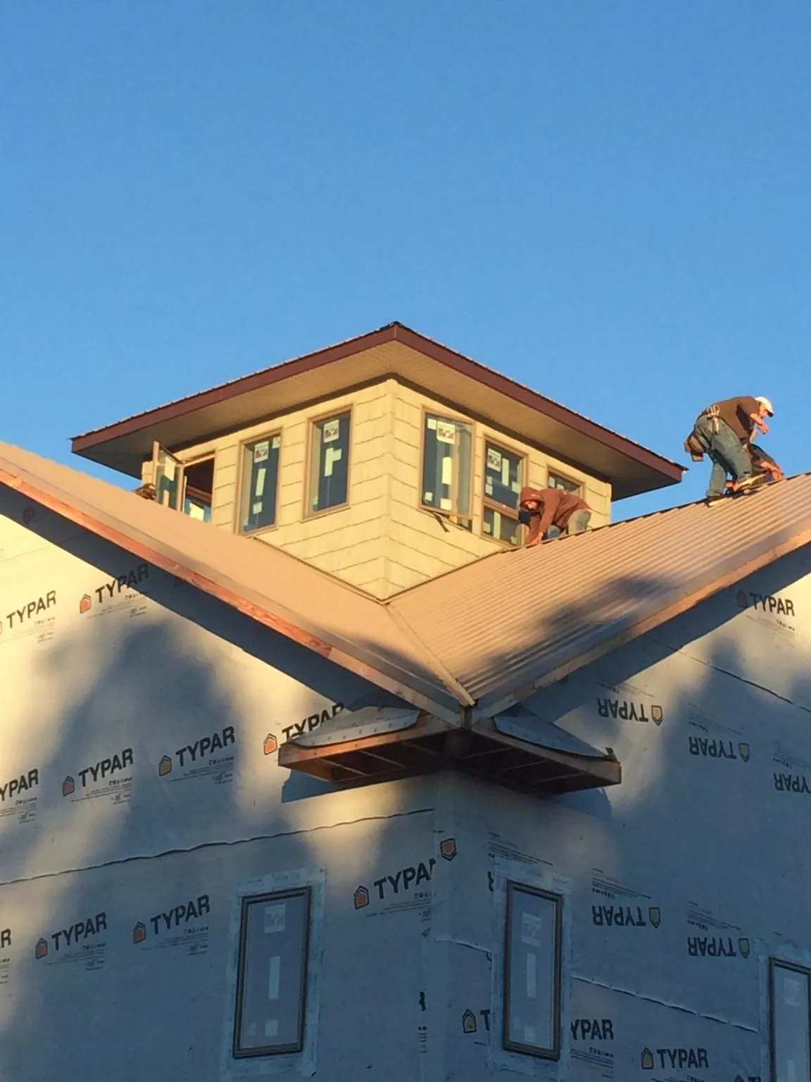 Roofers working around a rooftop cupola on a new metal roof at sunset — Roof Waterproofing in Woodlawn by Roofing Brothers
